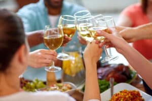 celebration, eating and holidays concept - hands clinking wine glasses